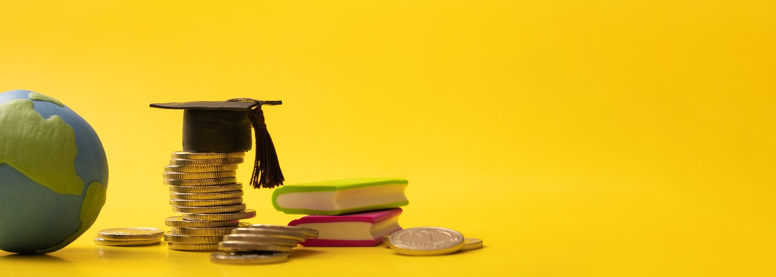 Banner with graduated cap with coins and globe on yellow backgro